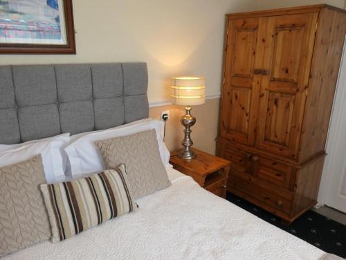 a bedroom with a bed with a lamp and a dresser at The Cumberland in Llandudno