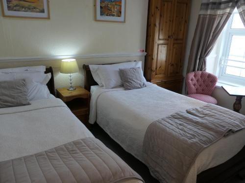 a bedroom with two beds and a chair and a window at The Cumberland in Llandudno