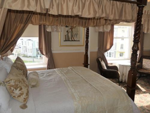 a bedroom with a canopy bed and a window at The Cumberland in Llandudno