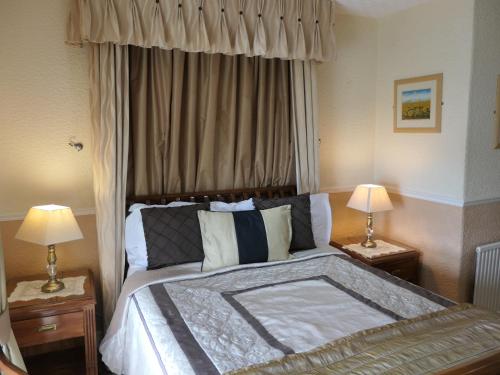 a bedroom with a large bed with two lamps at The Cumberland in Llandudno