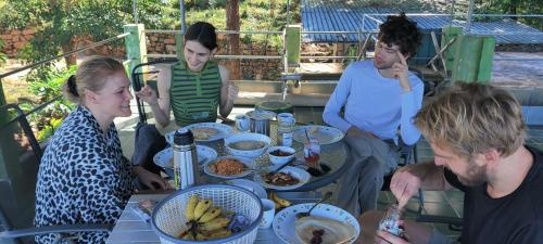 een groep mensen die rond een tafel zitten met eten bij Rohana Estate Lodging & Camping in Kandy