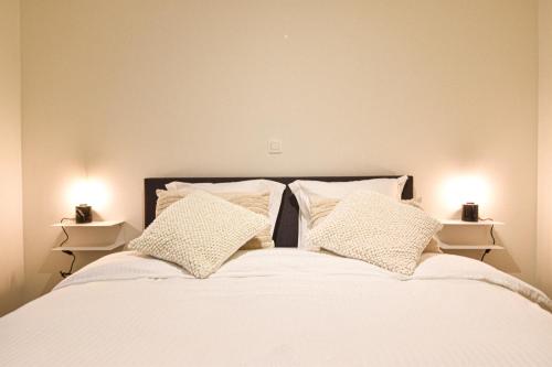 1 cama con sábanas y almohadas blancas y 2 luces en Miramar Residences - Luxurious Seaside Apartments, en Blankenberge