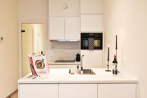 una cocina con armarios blancos y una botella de vino en una barra en Miramar Residences - Luxurious Seaside Apartments, en Blankenberge