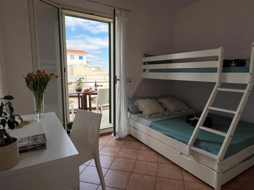 ein Schlafzimmer mit einem Etagenbett, einem Tisch und einem Schreibtisch in der Unterkunft Apartment SunShine in Marzamemi