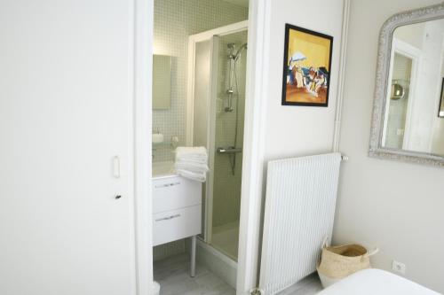 La salle de bains blanche est pourvue d'une douche et d'un miroir. dans l'établissement Duplex de 100m2 avec 3 chambres vue mer, à Royan