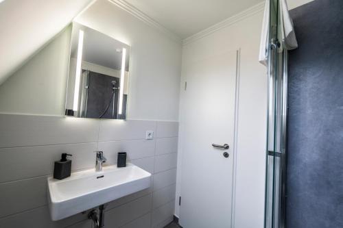 a white bathroom with a sink and a mirror at Hökis-Zimmervermietung 3 in Brande-Hörnerkirchen