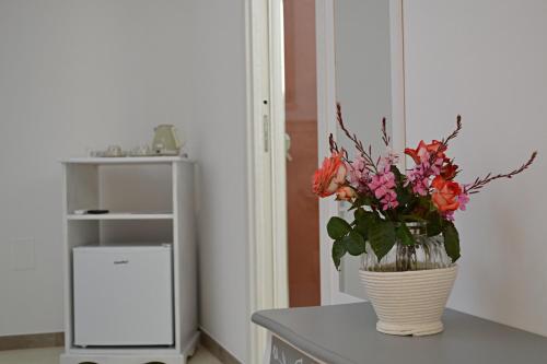 eine Vase Blumen auf einer Theke mit einem Schrank in der Unterkunft Arbor Exclusive in Ugento