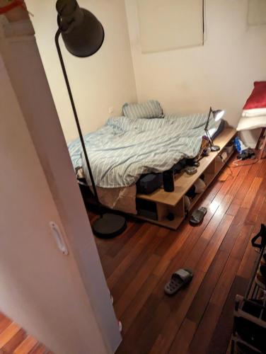 een slaapkamer met een bed met een lamp en een houten vloer bij chambre canal st martin in Parijs