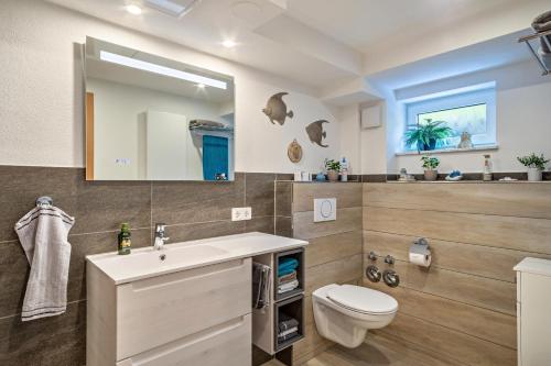een badkamer met een wastafel, een toilet en een spiegel bij Helms in Eriskirch