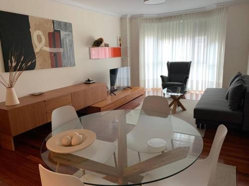 uma sala de estar com uma mesa de vidro e cadeiras em Piso a 5 minutos de la playa en SANTANDER! em Santander