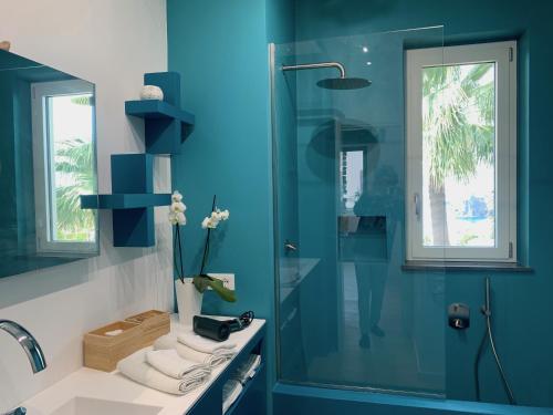 een blauwe badkamer met een wastafel en een douche bij Casa Nausica in Acitrezza