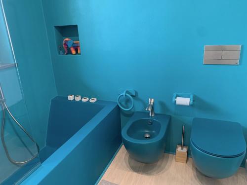 a blue bathroom with a toilet and a sink at Casa Nausica in Acitrezza