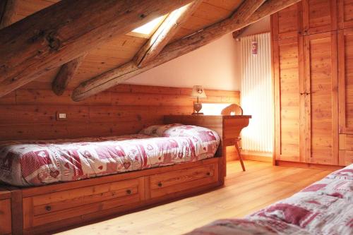 1 dormitorio con 1 cama, paredes de madera y suelo de madera en Attic in the centre of Asiago, en Asiago