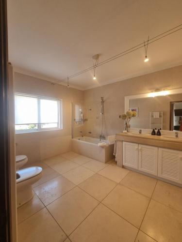 a bathroom with a tub and a toilet and a sink at Vila De Sol in Sesimbra