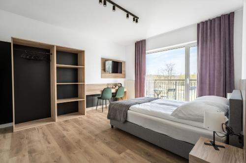 1 dormitorio con cama, escritorio y ventana en Morski Piasek, en Grzybowo