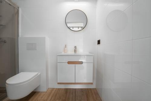a white bathroom with a toilet and a mirror at Morski Piasek in Grzybowo