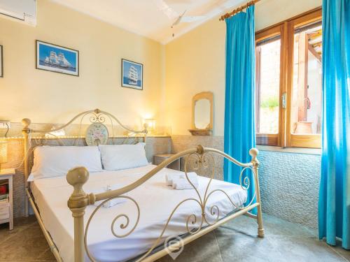 a bedroom with a metal bed with blue curtains at Casa Ida in Putzu Idu