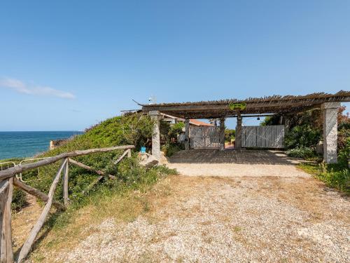 a dirt road next to the ocean with a fence at Casa Ida in Putzu Idu