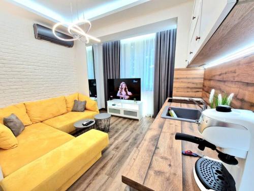 a living room with a yellow couch and a tv at The Little Prince studio in Varna City