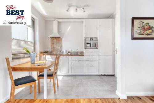 a kitchen with white cabinets and a wooden table at The Best Stay Central Apartment Gdansk in Gdańsk