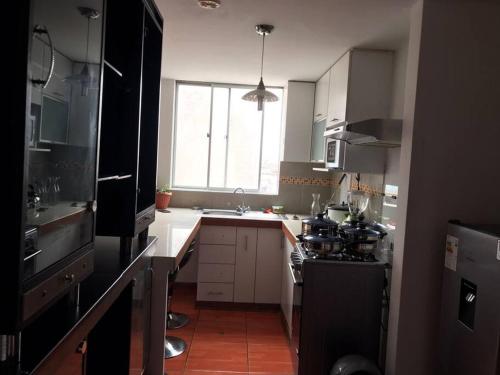 cocina con fogones, fregadero y ventana en Hermoso Duplex en Chorrillos, en Lima