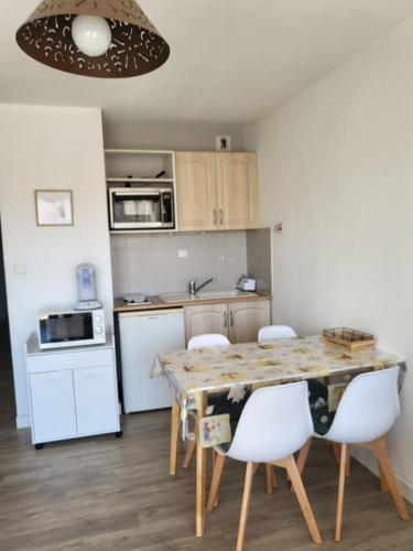 une cuisine avec une table et des chaises dans une pièce dans l'établissement Carnon Ouest Studio cabine 2 min à pied plage, à Mauguio