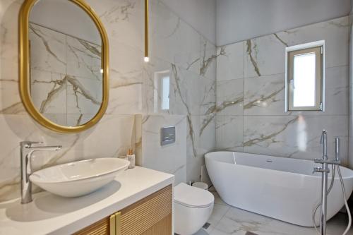 y baño con bañera, lavabo y espejo. en Villa Silentium Ionia by PosarelliVillas, en Argyroupolis