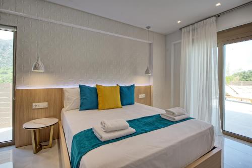a bedroom with a large bed with blue and yellow pillows at Villa Silentium Ionia by PosarelliVillas in Aryiroúpolis