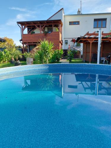 a swimming pool with blue water in front of a house at Penzion U Ježů - Ubytování in Pasohlávky