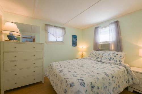 a bedroom with a bed and a dresser and two windows at 131 #3 North Shore Boulevard East Sandwich - Waters Edge #3 in Sandwich
