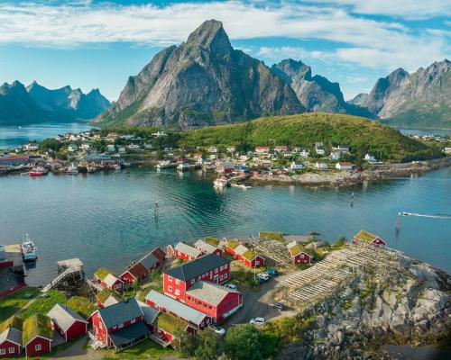 eine Luftansicht einer kleinen Stadt auf dem Wasser mit Bergen in der Unterkunft Reine Rorbuer - by Classic Norway Hotels in Reine