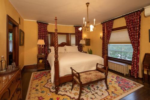 a bedroom with a bed and a chair and a window at Cartier Mansion in Ludington