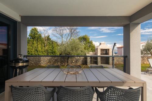 a wooden table on a patio with a view of a yard at Villa RINA - 3 bedroom with private pool in Krk