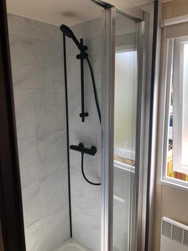 um chuveiro com uma porta de vidro na casa de banho em Grand mobil home exposé sud, 2 salles de bain em Onzain