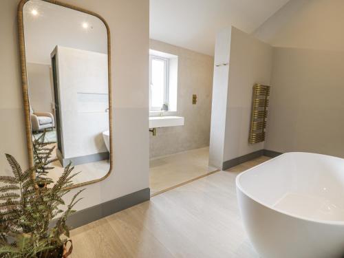a bathroom with a white tub and a mirror at Garden House in Amlwch