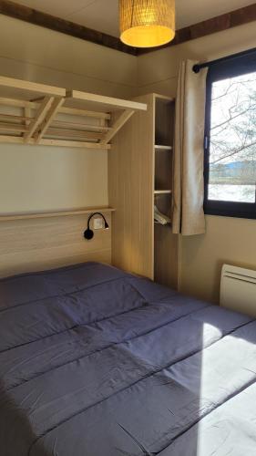 een groot bed in een kamer met een raam bij Camping Les Ballastières - Vosges du Sud in Champagney