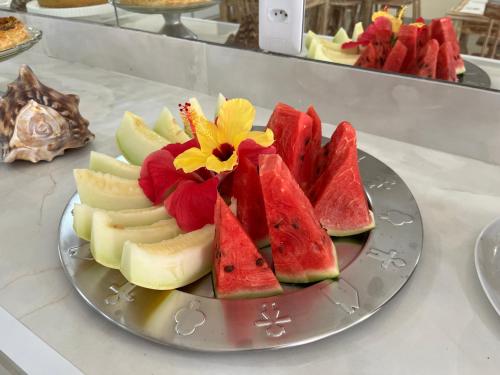ein Teller mit Wassermelonenscheiben und einer Blume darauf in der Unterkunft Pousada Donna Maraka in Porto De Galinhas