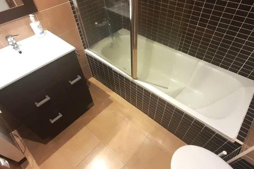 een badkamer met een bad, een wastafel en een toilet bij Apartamento Playa Foz in Foz