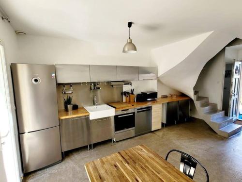 una cocina con electrodomésticos de acero inoxidable y una escalera en Maison de village 4 étoiles avec piscine privee, en Villars