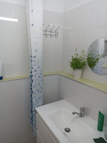 uma casa de banho branca com um lavatório e um espelho em הבית של יעל em Tel Aviv