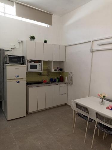 uma cozinha com armários brancos, uma mesa e um micro-ondas em הבית של יעל em Tel Aviv