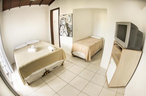 Habitación pequeña con 2 camas y TV. en Hi Adventure en Florianópolis