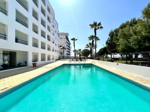 a swimming pool in front of a building at Quarteira Ocean Breeze 1 With Pool by Homing in Quarteira