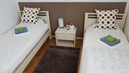 2 Einzelbetten in einem Zimmer mit einem Nachttisch in der Unterkunft Jovì`s Apartment in Tar