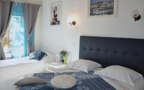 - une chambre avec 2 lits et une tête de lit bleue dans l'établissement Hôtel Les Mimosas, à Bormes-les-Mimosas