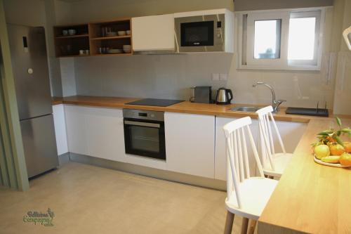 a kitchen with white cabinets and a table with a bowl of fruit at Bellisima Campagna Cabin Pelekapina - Chania Crete in Chania Town