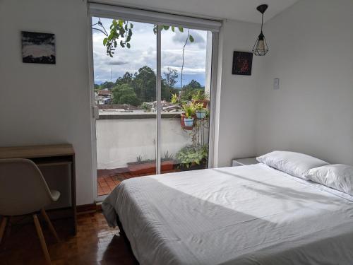 a bedroom with a bed and a large window at Habitación en COLIVING penthouse centro histórico in Popayan
