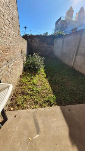 una pared de ladrillo junto a un campo de hierba en Alquiler por día. en Firmat