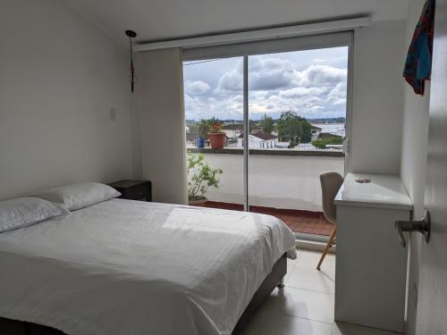 a bedroom with a bed and a large window at Habitación en penthouse en el centro histórico in Popayan