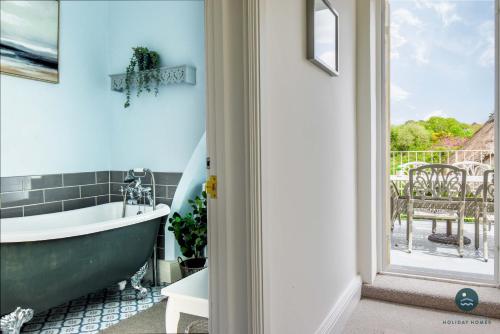 a bathroom with a green tub and a window at The Old Chapel - Exclusive Retreat in Weymouth